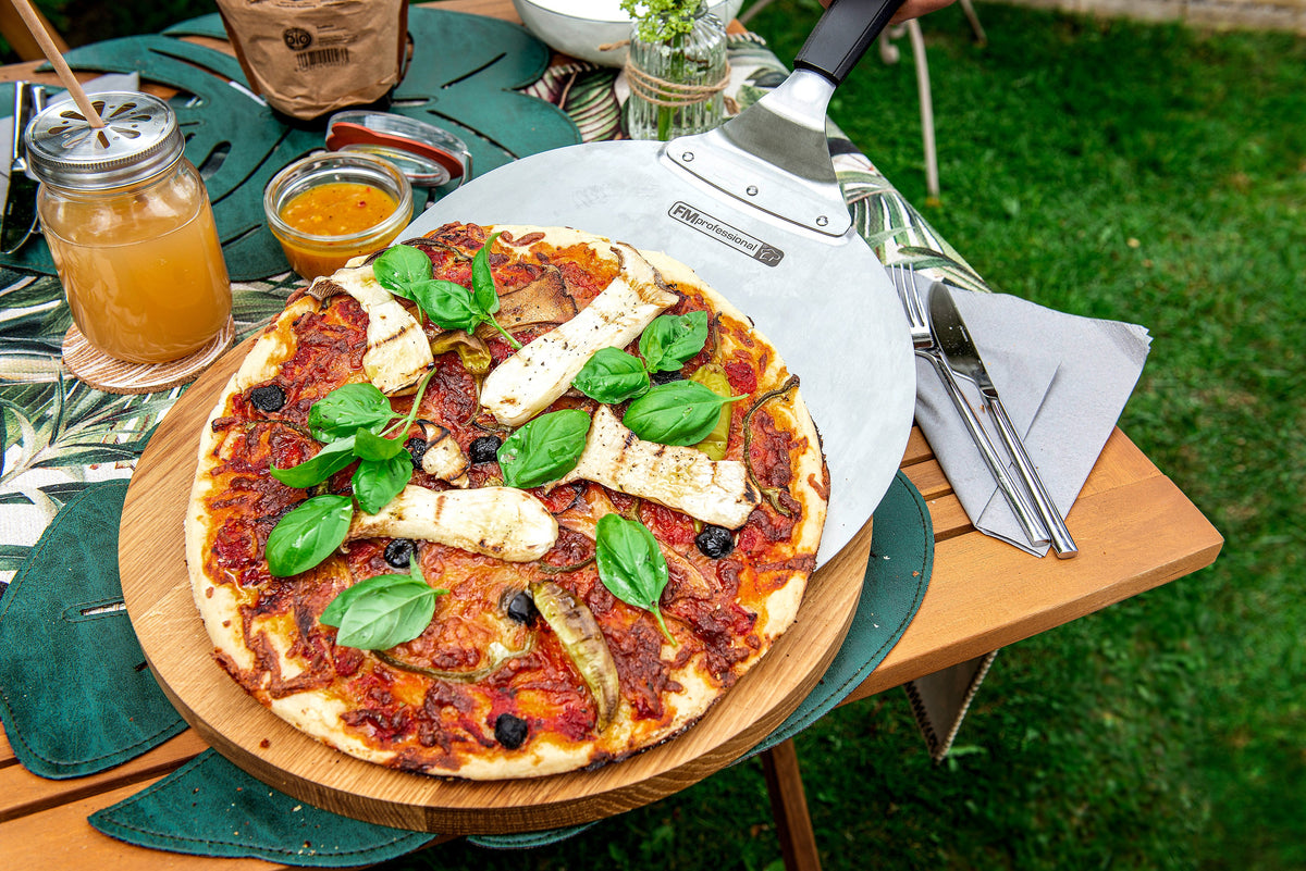 Pizza maison sur une pelle à pizza, servie sur une table de jardin